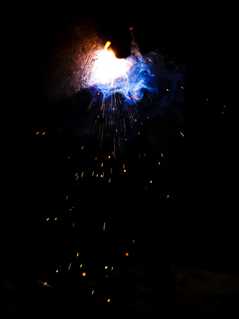 Flame of fire and sparks from welding metal at night .