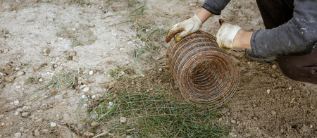 Worker unwinds a metal mesh for pouring concrete .の写真素材