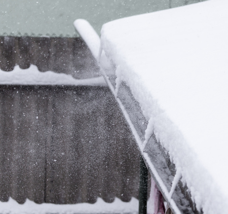 Snow on the roof of the house as a background .