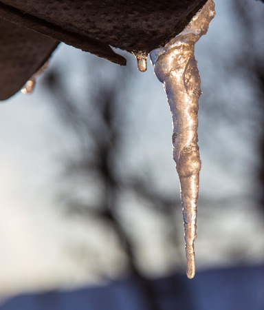 Icicles hang from the roof in winter .の写真素材
