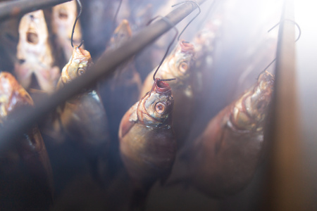 Salted fish is smoked on hooks in the smokehouse