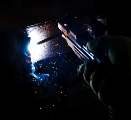 Flame of fire and sparks from welding metal at night .