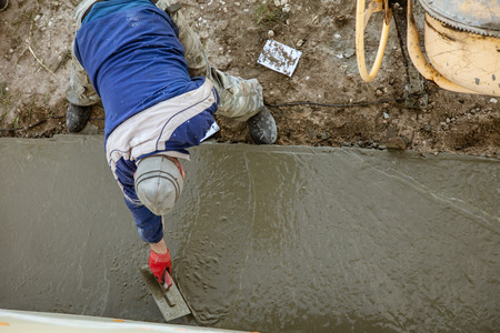 Workers pour concrete solution at a construction site .