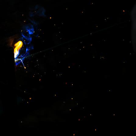 Flame of fire and sparks from welding metal at night .