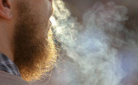 The man with a beard smokes in nature .の写真素材