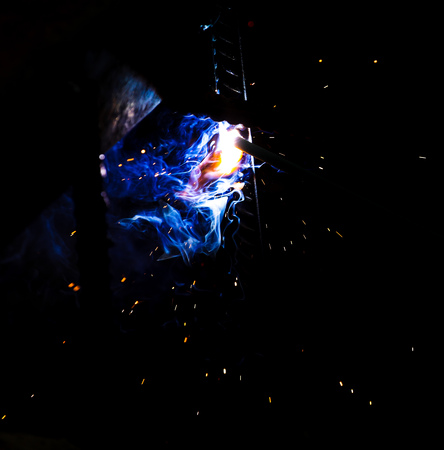 Flame of fire and sparks from welding metal at night .