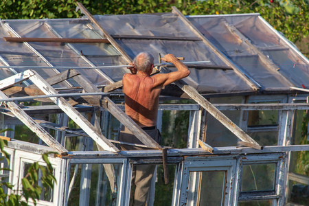 The old man repairs the greenhouse in the garden .の写真素材