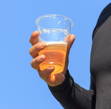 Beer in a plastic cup in hand in natureの写真素材
