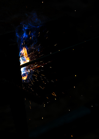 Flame of fire and sparks from welding metal at night .