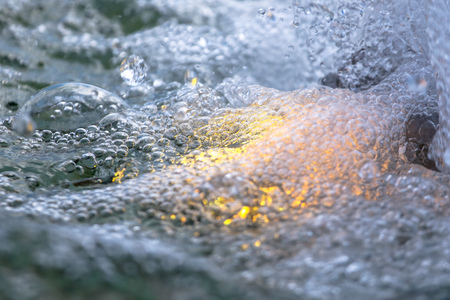 Yellow water in the fountain as abstract background .