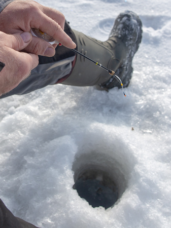 Man catches fish on ice in winter .の写真素材