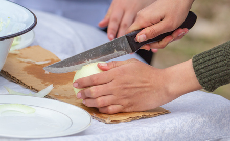 Girl slices onions with a knife on the table .の写真素材