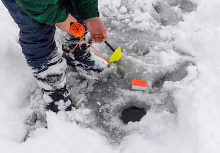 Boy fishing with a fishing rod on the ice in winter .の写真素材