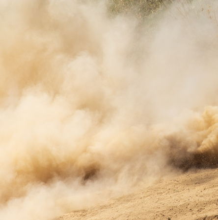 A cloud of dust from cars on nature as a background