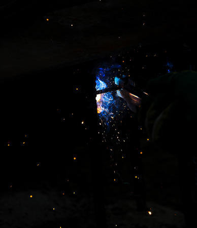 Flame of fire and sparks from welding metal at night .