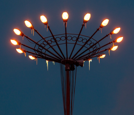 Lanterns burning on a pole at night in the park .