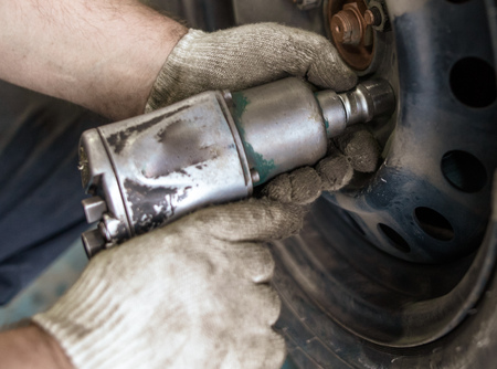Tightening bolts on wheels of cars in the workshop .の写真素材