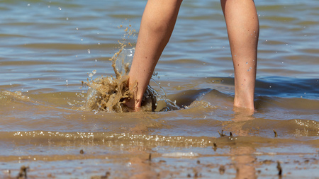 Feet of a girl walking by the sea .