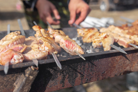 A man fries kebabs on skewers on the grill .の写真素材