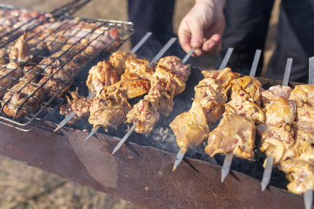 A man fries kebabs on skewers on the grill .の写真素材