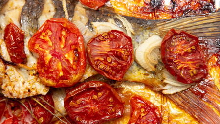 Baked fish in the oven with tomatoes .