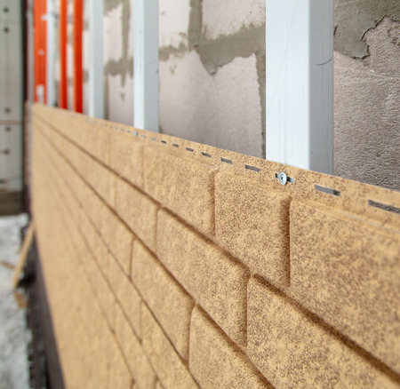 Installing brick siding on the wall of the house .