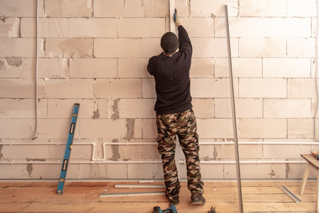 Worker mounts a profile on a wall at a construction site .の写真素材