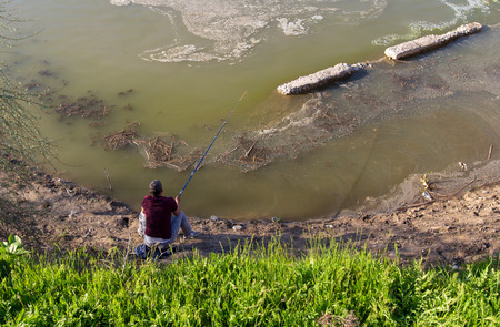 Fisherman catches fish on the shore of the pond.の写真素材