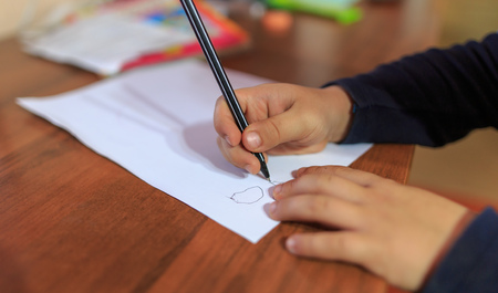 Boy writes pen on a sheet of paper.の写真素材