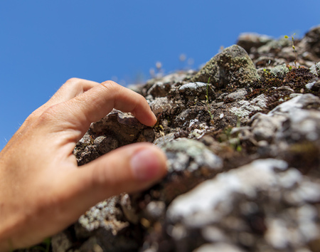 Hand on the stone rock in the mountains as background.