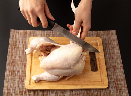 Cutting chicken carcass on a board on a black background.の写真素材