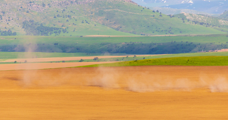 Dust from a tractor working in a field in spring .の写真素材