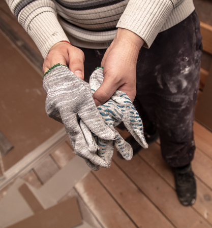 Worker takes off gloves from hands at a construction site.の写真素材