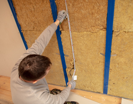 Worker installs drywall on the walls in the room.