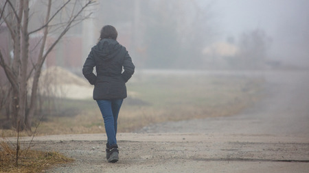 The girl goes on the road in the fog.