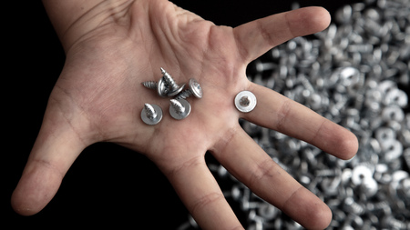 Sharp screws in hand on black background.の写真素材