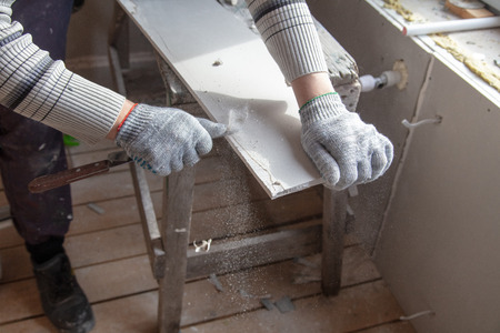 Worker cuts with a knife drywall repair.