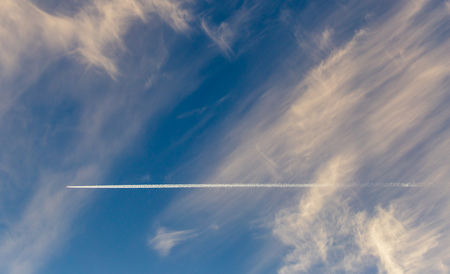 Trail from the plane in the sky at sunset.の写真素材