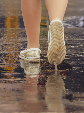 Woman's legs crossing the road in the rain .の写真素材