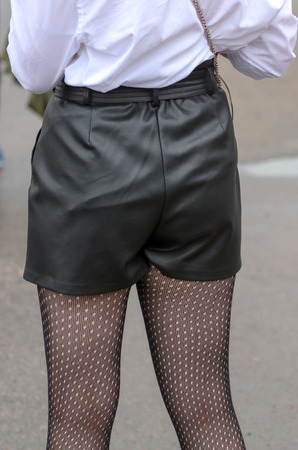 Girl's legs in black leather shorts .の写真素材