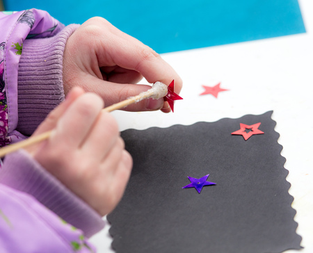 The girl glues the stars on a sheet of paper .の写真素材