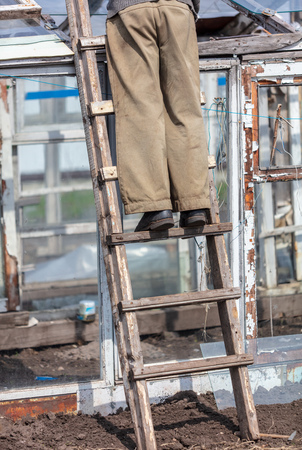 Feet on the stairs repairing a greenhouse in the garden.の写真素材