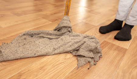 The girl washes the floor with a rag in the room.