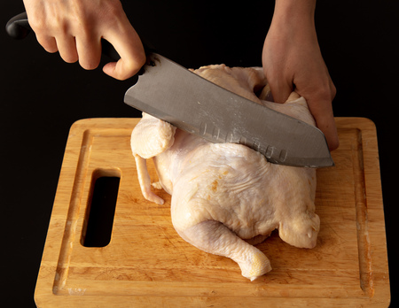 Cutting chicken carcass on a board on a black background.の写真素材