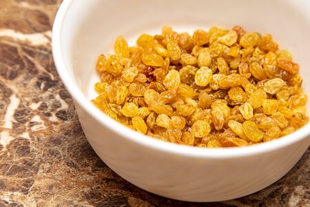 Yellow raisins in a plate on the tableの写真素材