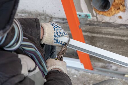 A worker installs a metal profile on the walls of a siding house.の写真素材