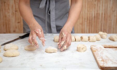 The hostess cuts the dough in the kitchen .