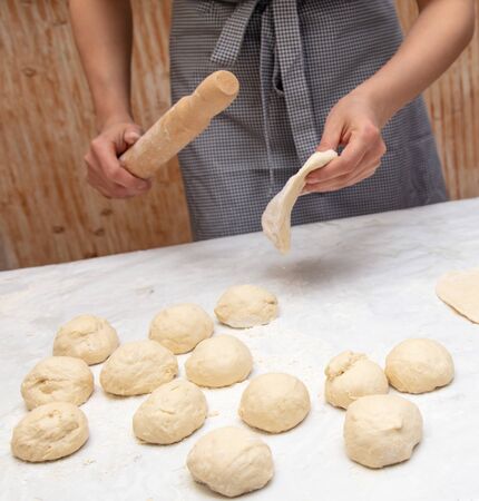Girl rolls the dough in the kitchen .の写真素材