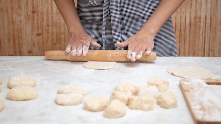 Girl rolls the dough in the kitchen .