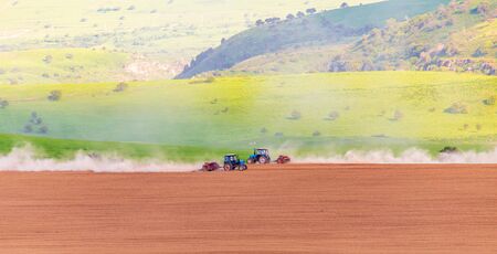 Dust from a tractor working in a field in spring .の写真素材